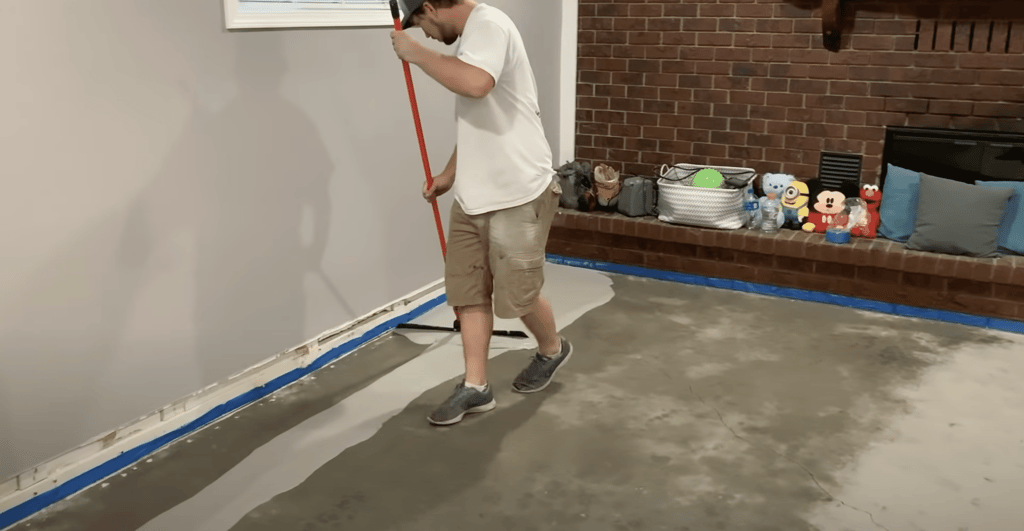 After taping the edges, we begin by putting our first coat of concrete overlay down on the floor using a squeegee.