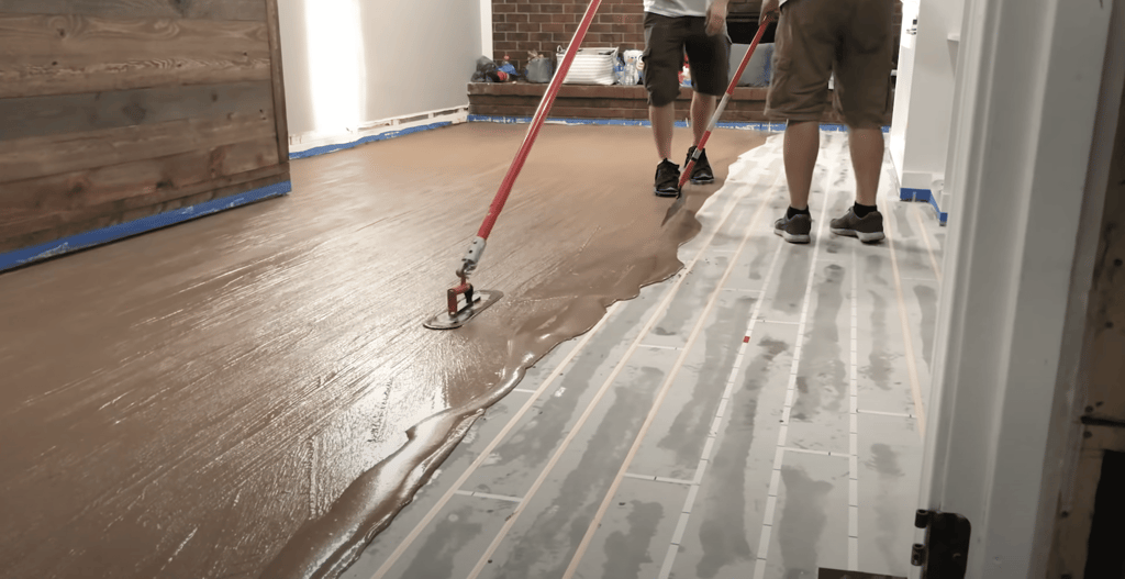 While one person is using a squeegee, the second person is using a pool trowel to get the wood grain texture in our concrete overlay.