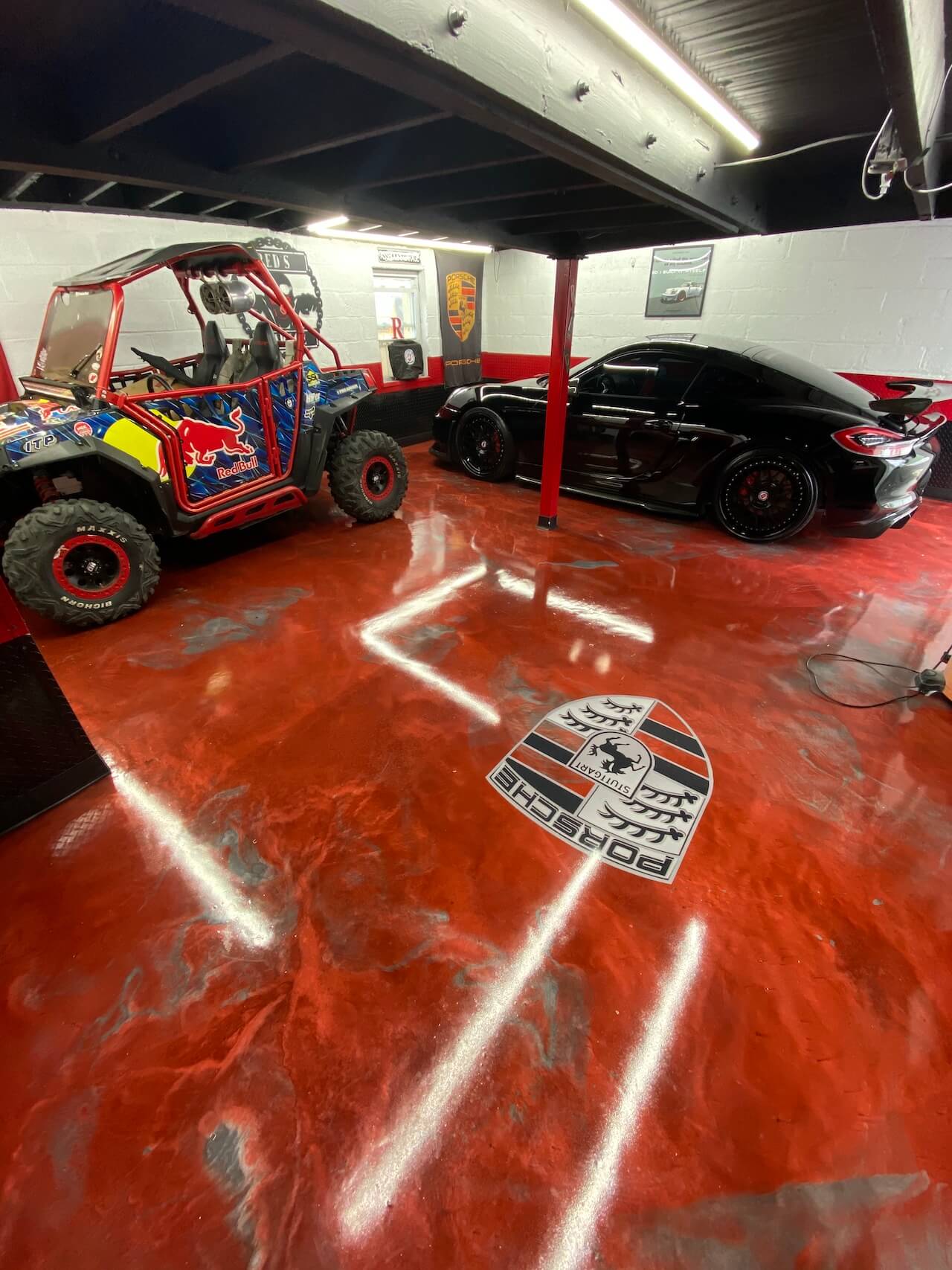 A red and gray epoxy floor with a Porsche car logo inlayed in the center.
