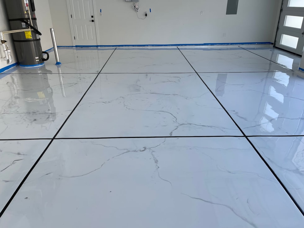 A white marble-look epoxy floor with distinct black grout lines installed in a garage.  The white marble look features subtle gray highlights.