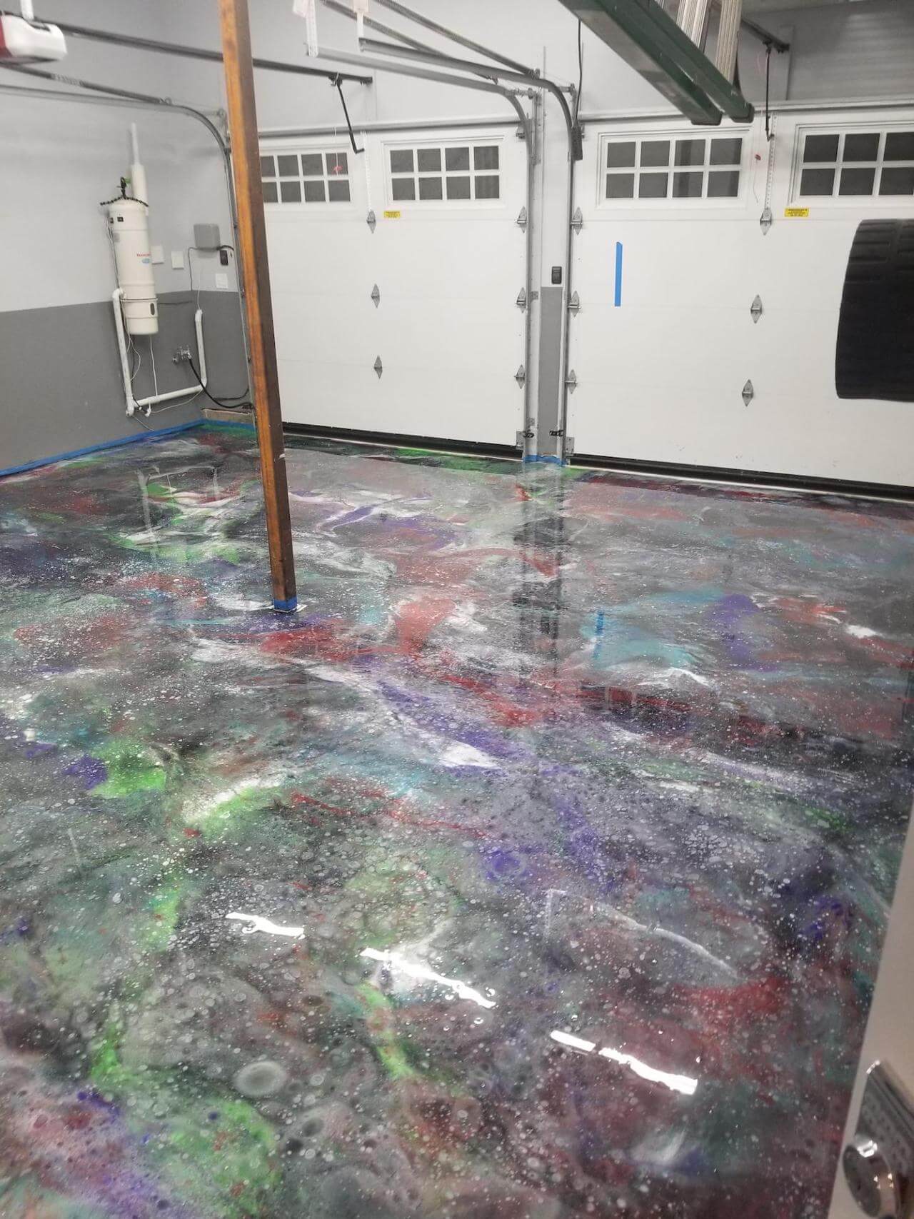 A metallic epoxy "Galaxy" garage floor featuring many different colors (red, green, blue, purple, turquoise, and black) all blended together to create this unique space