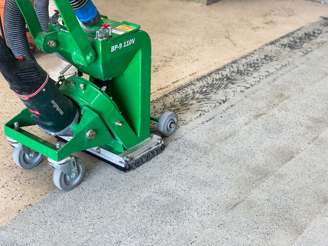 A shot blaster preparing the concrete surface for an epoxy floor installation.