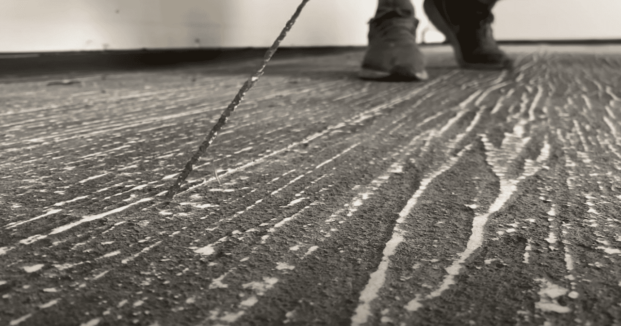 Removing the filament tape to expose the grout lines of our hardwood overlay floor.