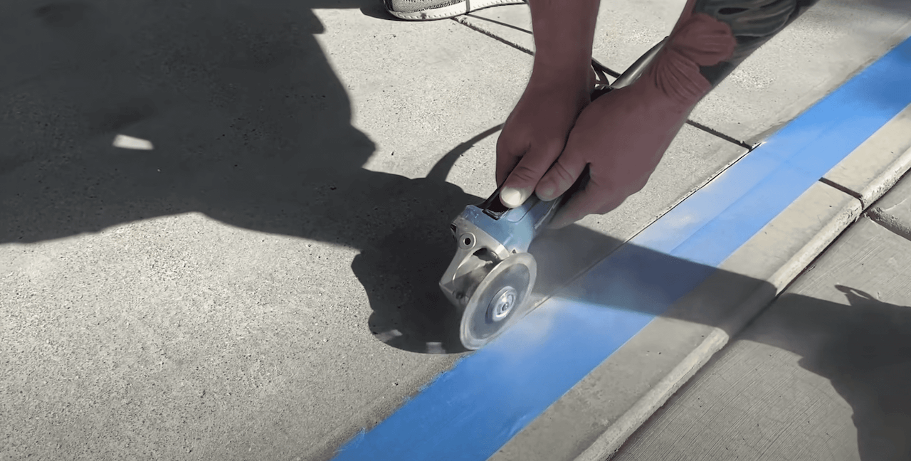 Using an angle grinder with a 4-inch diamond cutting wheel to make a 1/8th inch depth cut to act as a termination point for the overlay.