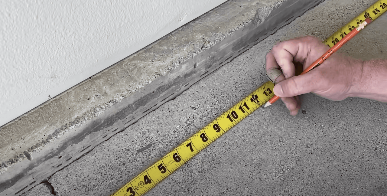 Measuring and marking the spacing on the concrete to determine the size of our wood planks.