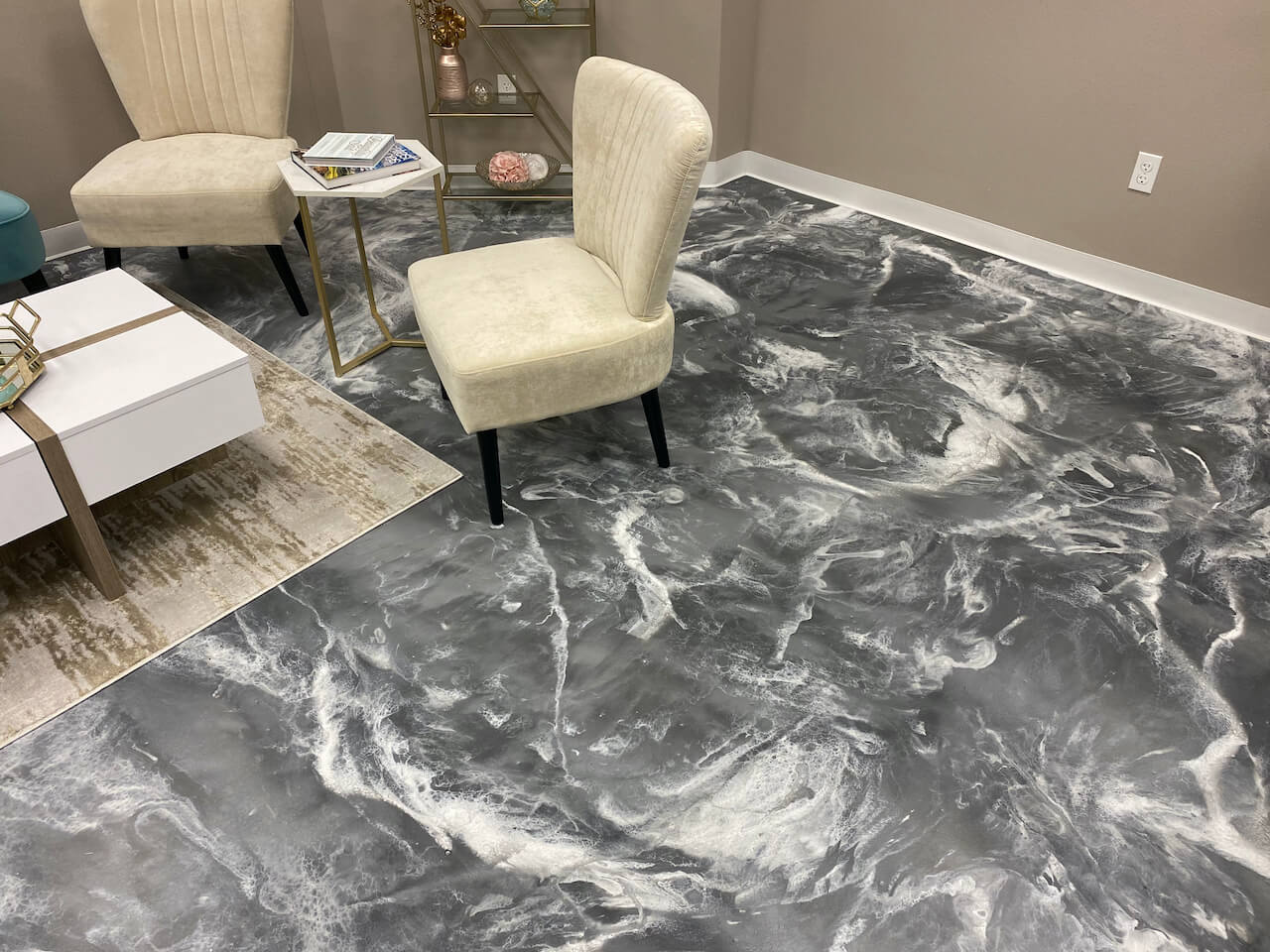 An office waiting area with metallic epoxy floors featuring a slate gray base and white swirl highlights.