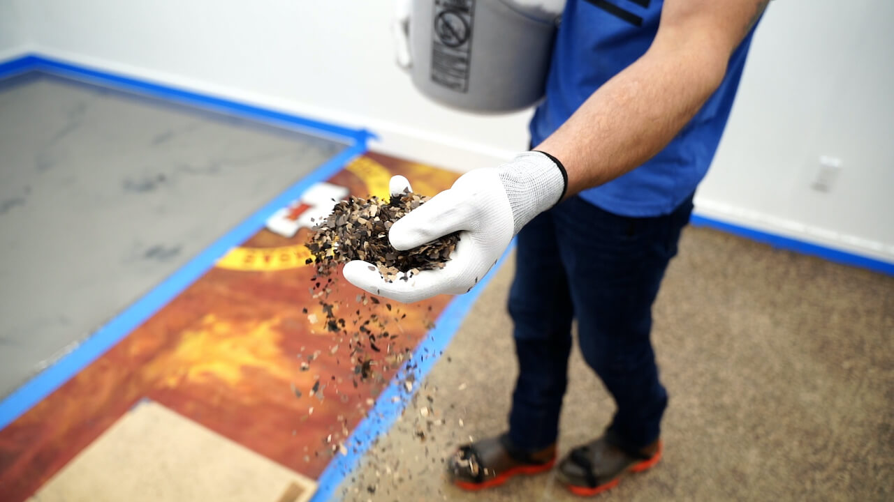 Spreading Leggari flakes on an epoxy floor to create a chip or flake floor.  This type of flooring is very popular in garages.