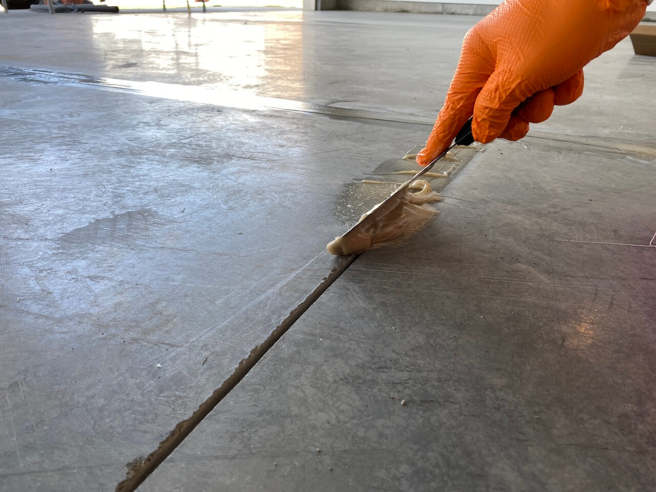 Applying patcher paste to the saw cuts in a concrete garage floor.
