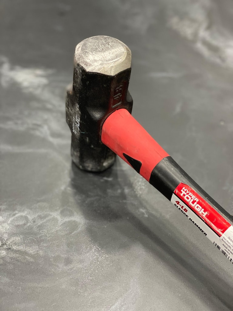 A sledge hammer slammed into an epoxy floor demonstrating the unparalleled strength of metallic epoxy.